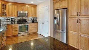 A kitchen with wooden cabinets, stainless steel appliances, and a granite countertop.