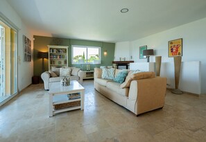 A living room with two sofas, a coffee table, a bookshelf, and a fireplace. - Luxury sea view villa in Les Issambres | Villa Panorama Azur (Les Issambres)
