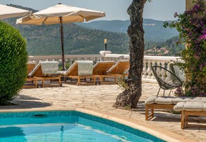 A poolside area with lounge chairs, umbrellas, and a view of the mountains. - Luxury sea view villa in Les Issambres | Villa Panorama Azur (Les Issambres)