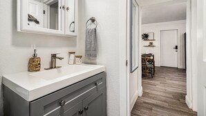 Een badkamer met een wit wastafel, een spiegel en een handdoek aan de muur.