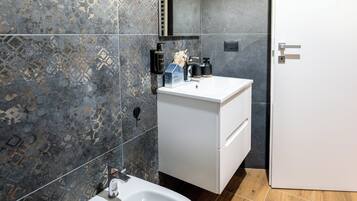 Un baño moderno con un lavamanos blanco, un bidé y un espejo sobre el lavamanos.