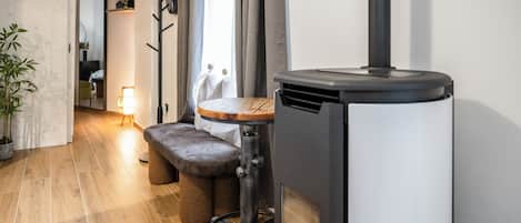 Una cocina moderna con estufa de leña, un banco y una planta en maceta.