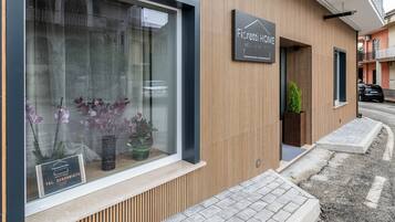 Un bâtiment moderne avec une façade en bois, une grande fenêtre ornée de plantes et une enseigne indiquant « Fiorietti HOME ».
