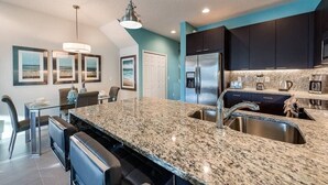 A modern kitchen with granite countertops, stainless steel appliances, and dark cabinetry. - 3BR Home w/ Private Pool Near Disney (Clermont)