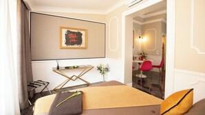 Una habitación de hotel con una cama, una pequeña mesa con un florero, una silla y un cuadro colgado en la pared.