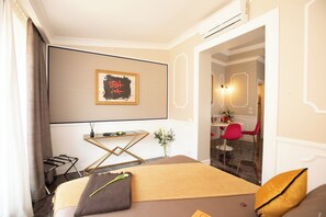 Une chambre d’hôtel avec un lit, une petite table sur laquelle est posé un vase de fleurs, une chaise et un tableau accroché au mur.