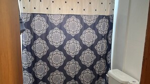 Une salle de bain avec un rideau de douche à motifs, des toilettes et un lavabo avec un plan de travail.