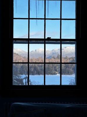 Ein Fensterblick auf schneebedeckte Berge und einen See.