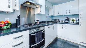 Een moderne keuken met witte kastjes, roestvrijstalen apparatuur en een zwart aanrecht.