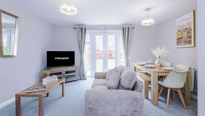 Een moderne woonkamer met een bank, een eettafel en een televisie.
