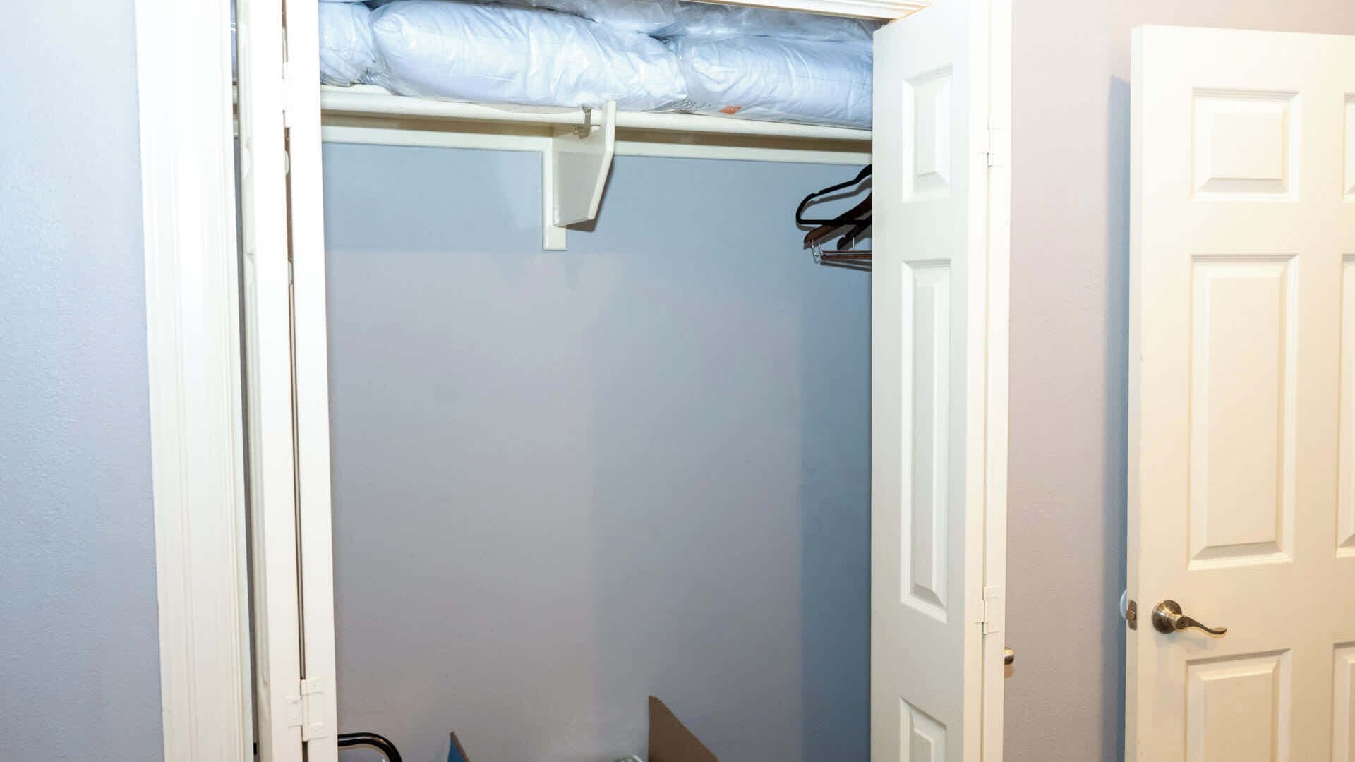 Un pasillo estrecho con una puerta blanca a la derecha y un armario con puerta blanca a la izquierda.