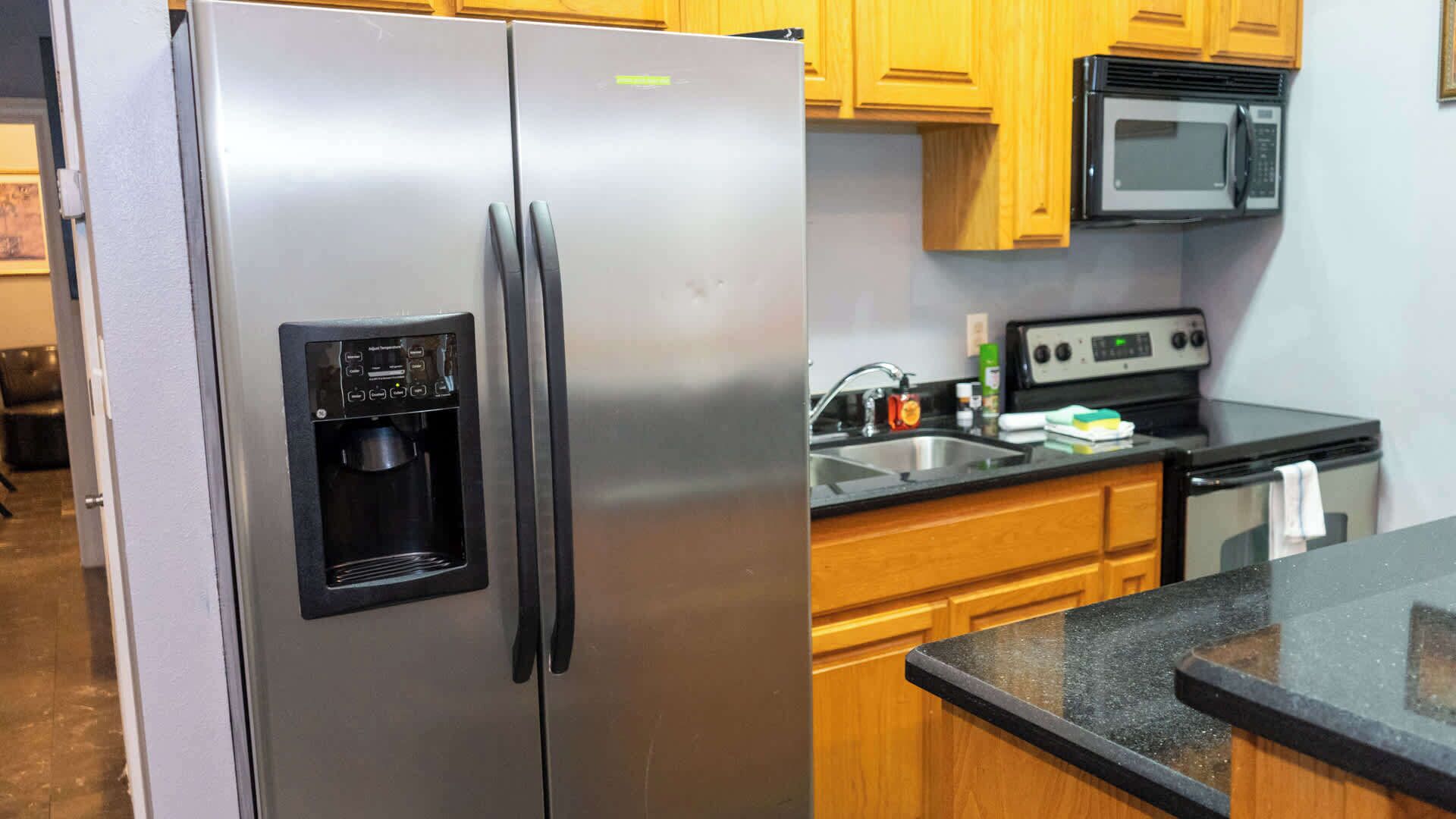 A kitchen with stainless steel appliances, including a refrigerator with a water dispenser, a microwave, and a stove.