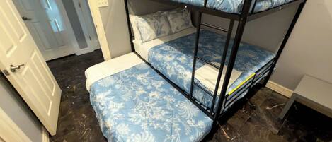 A bunk bed with floral bedding in a room with a tiled floor and a door in the background.