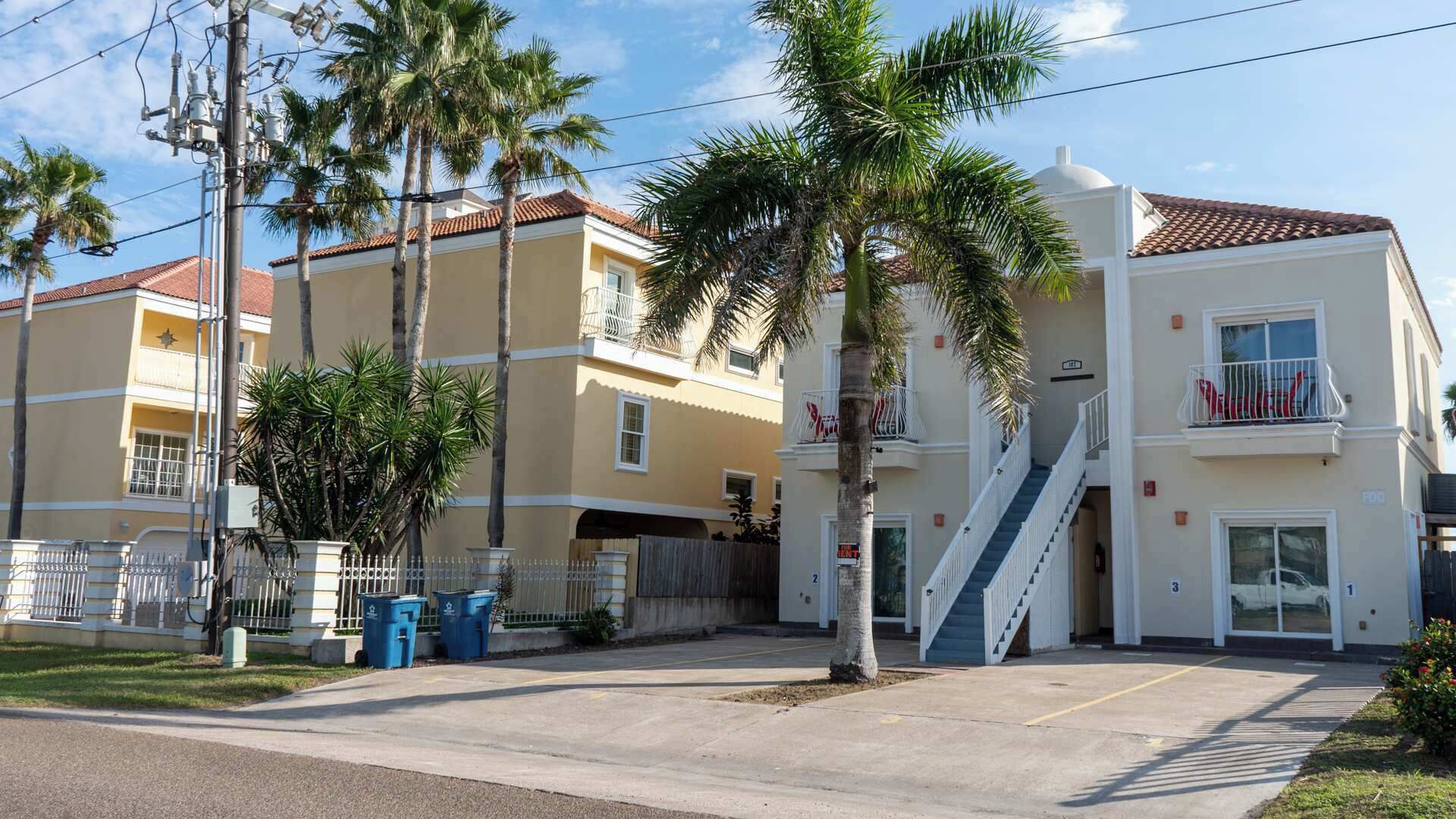 A multi-story building with a central staircase, balconies, and a parking area.