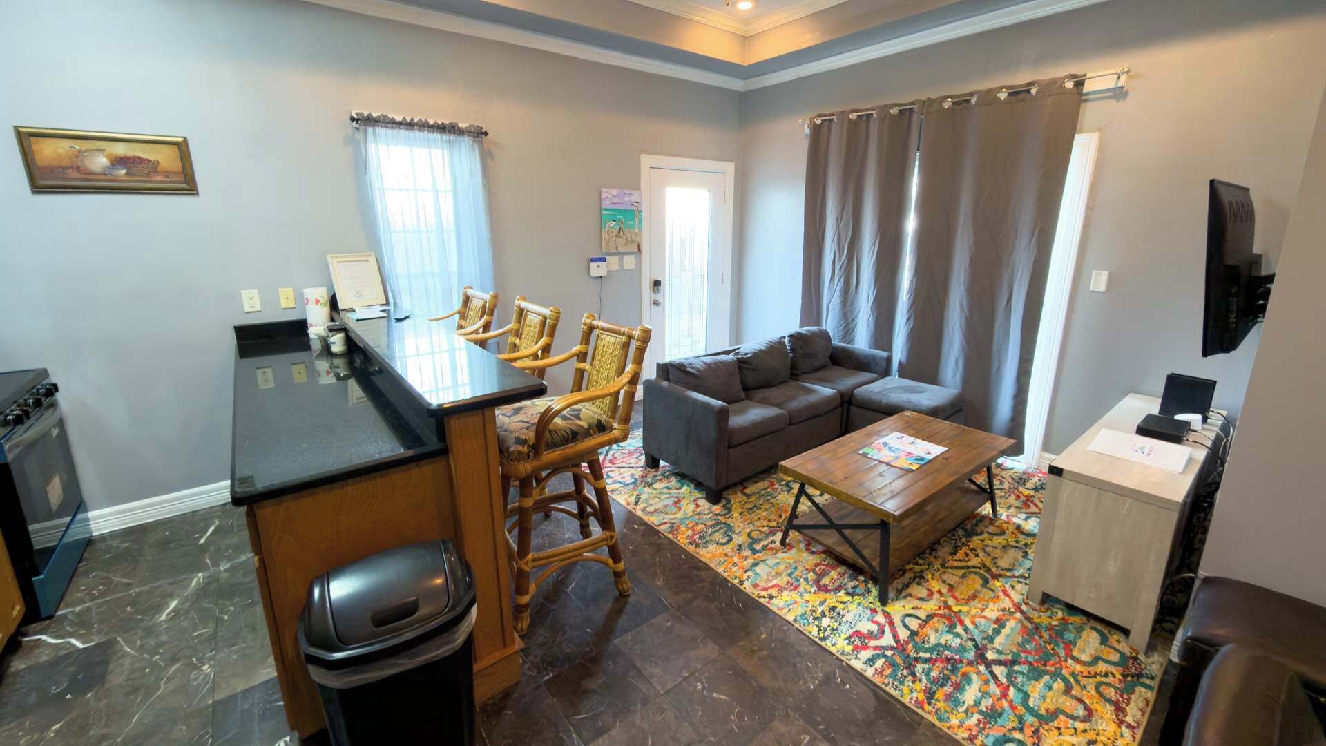 A compact living space with a kitchenette, a sofa, a coffee table, and a patterned rug.