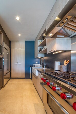 Eine moderne Küche mit Edelstahlgeräten, Holzschränken und einer blauen Akzentwand.