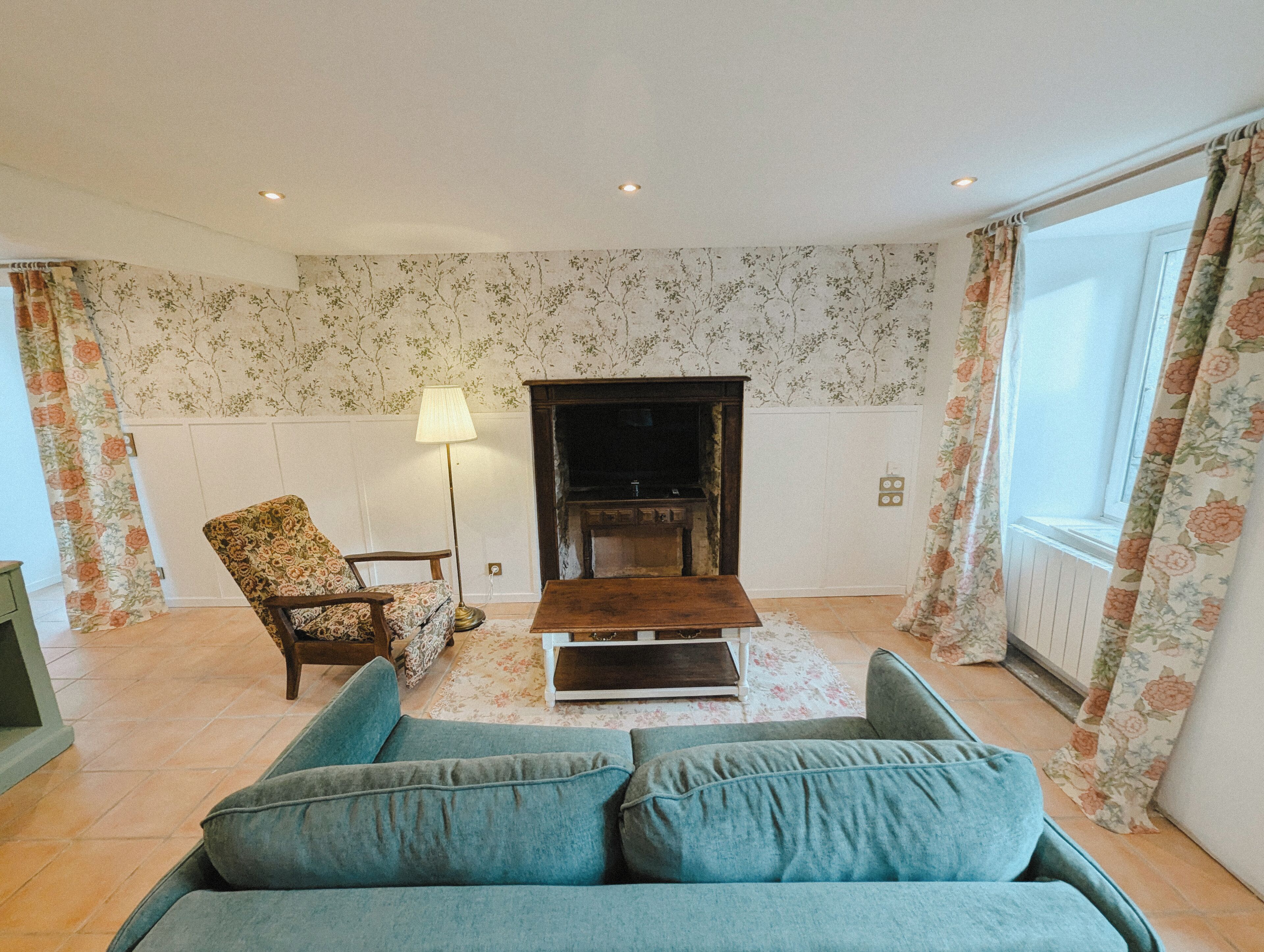 A living room with a sofa, a chair, a lamp, and a fireplace.