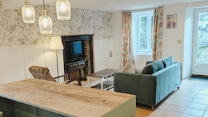 A spacious living area with a green kitchen island, a fireplace, and a sofa. - Bright English-style cottage apartment (Mazet-Saint-Voy)