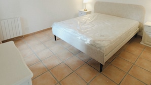 A bedroom with a bed, a bedside table, a lamp, and a radiator. - Bright English-style cottage apartment (Mazet-Saint-Voy)