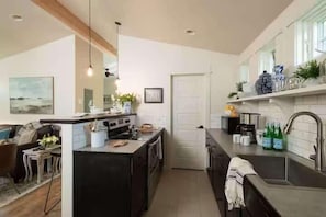 A modern kitchen with a central island, built-in oven, and a large window.