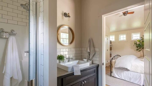 Ein Badezimmer mit Glasdusche, Waschbecken mit Spiegel und einem Handtuch an der Wand.
