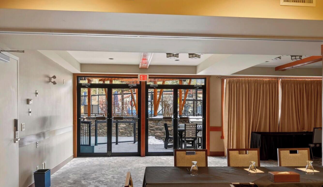 Un hall d’hôtel comprenant un comptoir d’accueil, une porte vitrée donnant sur l’extérieur et un espace détente avec des tables et des chaises.