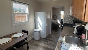 Une cuisine compacte équipée d’un réfrigérateur, d’un évier et d’un coin repas avec des chaises et une table.