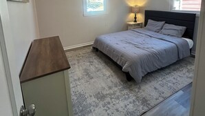 Une chambre à coucher avec un lit, une table de chevet, une lampe et une petite fenêtre.