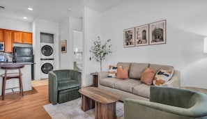 A modern living room with a sofa, two armchairs, a coffee table, and a dining area with a bar stool. - Casa Agave, a stylish Spanish one-bedroom lower-level condo. (La Quinta)