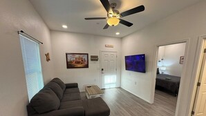 Una sala moderna con un sofá modular, una mesa de comedor y un ventilador de techo.