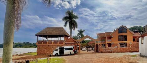 A hotel with a large open gate, a white van parked in front, and a palm tree.