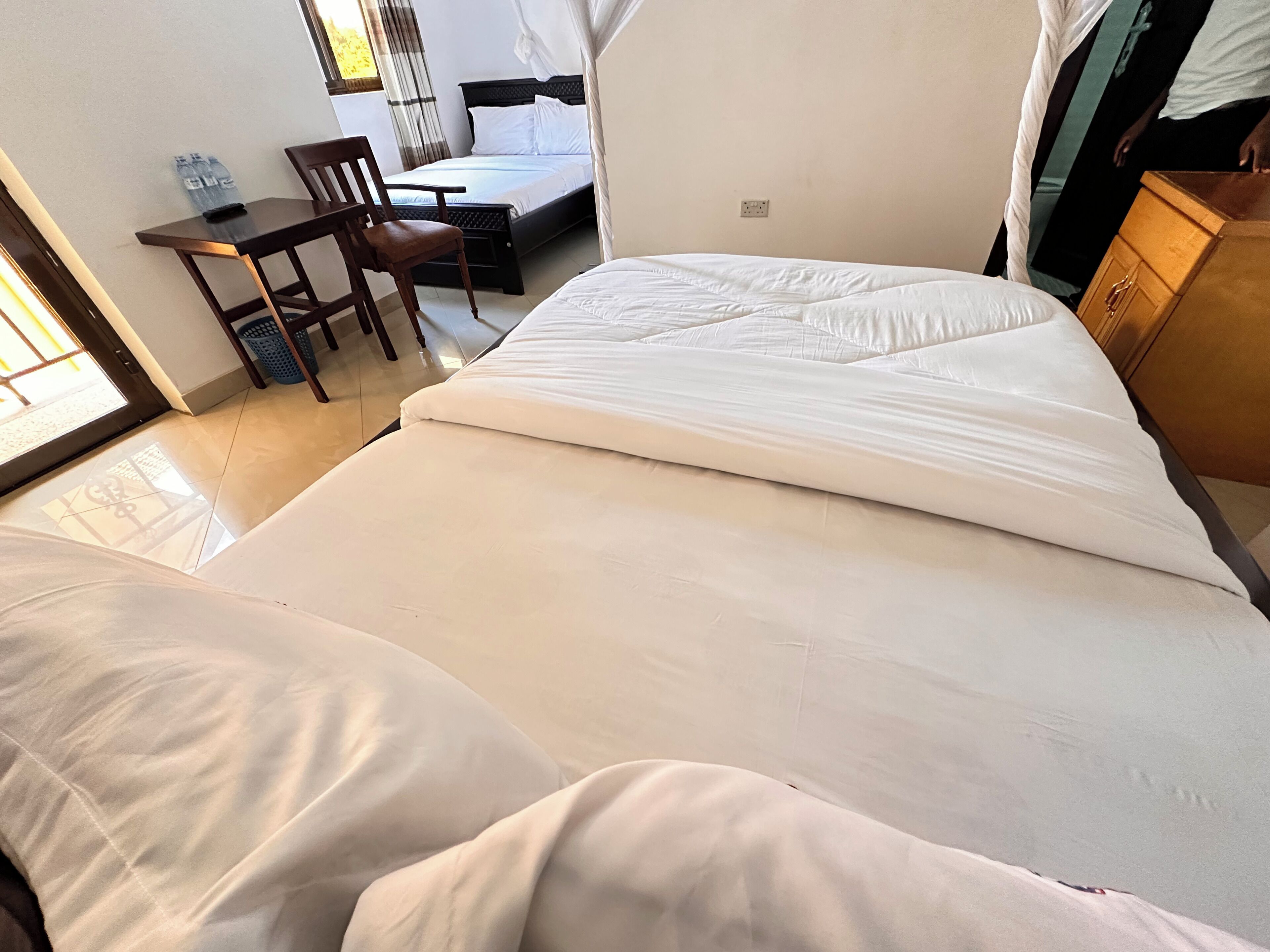 A hotel room with a bed, a desk, a chair, and a wardrobe.