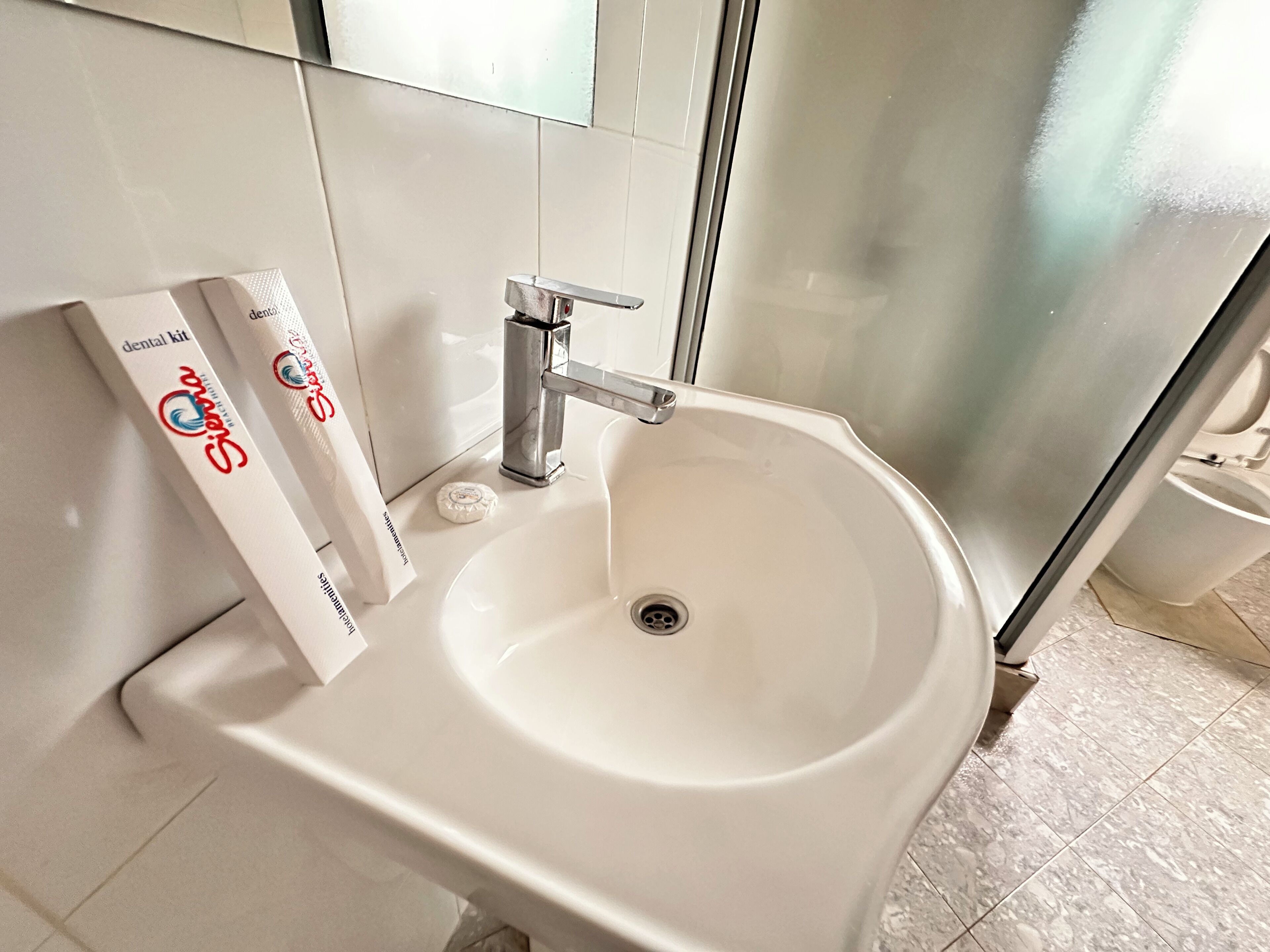 Een badkamer met een witte wastafel, een spiegel en een tandenborstelhouders met een tandenborstel.