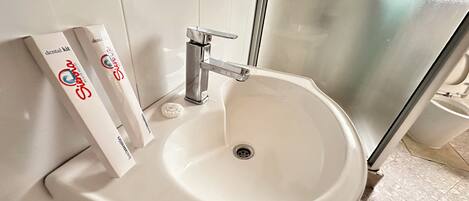 A bathroom with a white sink, a mirror, and a toothbrush holder with a toothbrush.