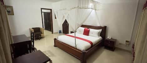 Un dormitorio con cama, mesita de noche, silla y una pequeña mesa con sillas.