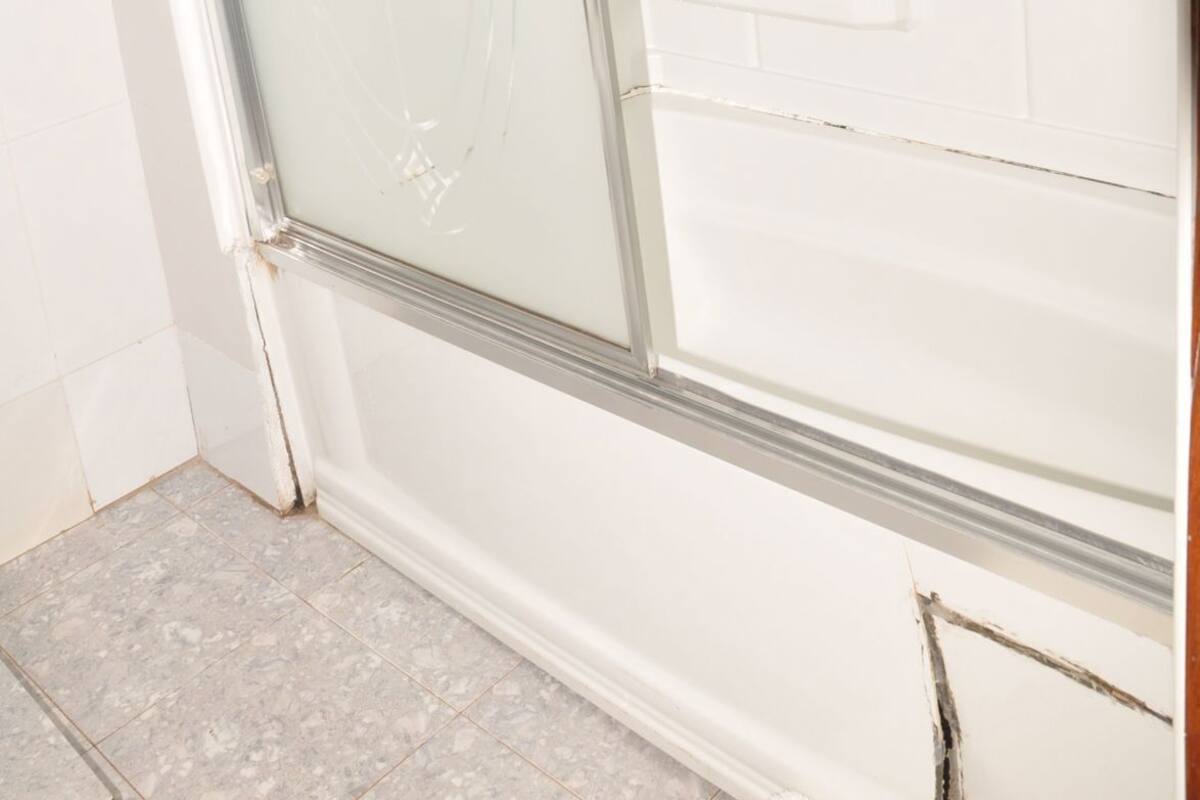 A bathroom with a glass shower enclosure, white tiled walls, and a visible towel rack.