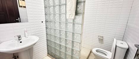 A bathroom with a sink, toilet, and shower with frosted glass doors.