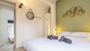 A hotel room with a bed, a wardrobe, a mirror, and a wall decoration. - Clos Fontaine House with garden, pool (Valras-Plage)