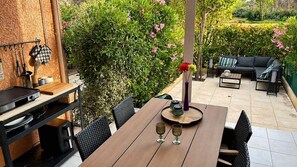 An outdoor dining area with a wooden table, chairs, a grill, and a sofa. - Clos Fontaine House with garden, pool (Valras-Plage)
