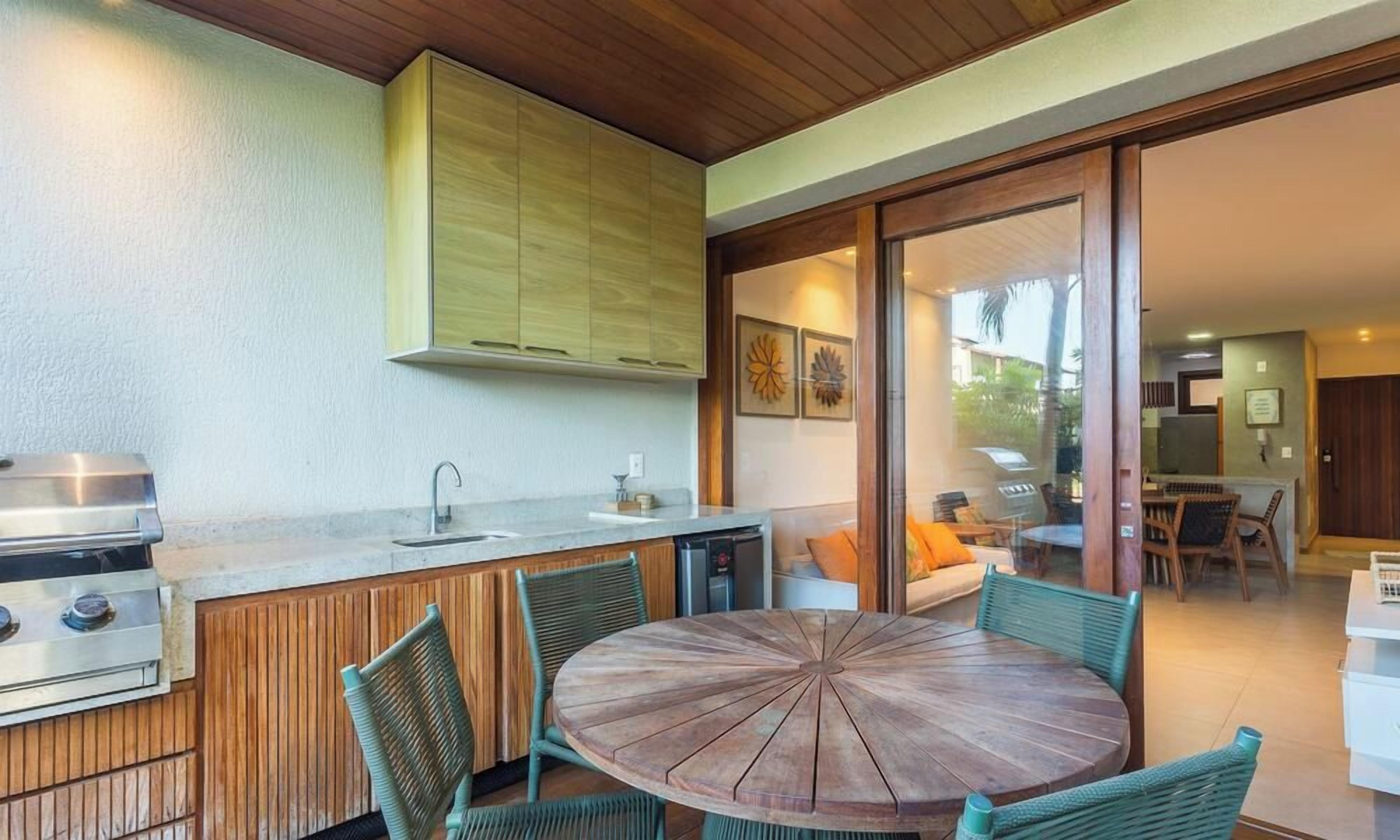 Un espace cuisine extérieur comprenant un barbecue, un évier et un coin repas avec des chaises et une table.