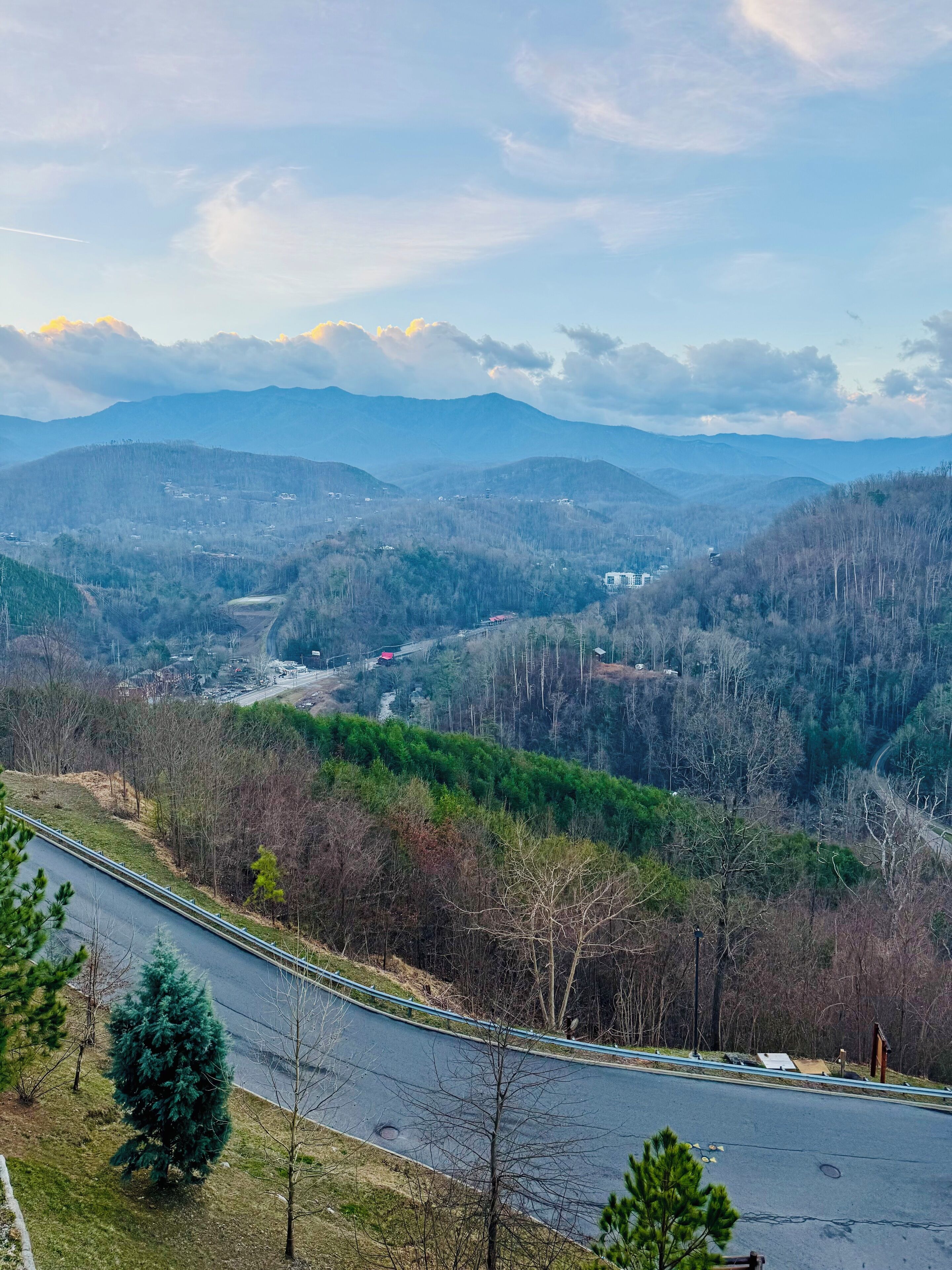 A winding road through a mountainous landscape with sparse vegetation and a few buildings in the distance.