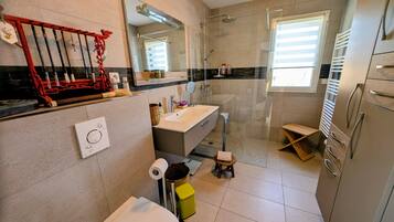 Une salle de bain moderne équipée de toilettes, d’un lavabo, d’une douche et d’un miroir.