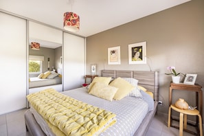 A bedroom with a bed, bedside tables, a mirror, and artwork on the wall.