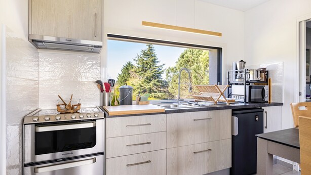 Een moderne keuken met een inbouwoven, een magnetron en een spoelbak.