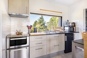 A modern kitchen with a built-in oven, a microwave, and a sink. - Charming Gîte “Un Thé Sur La Loire” with Private Terrace, Garden, and Wi-Fi (Ballan-Miré)