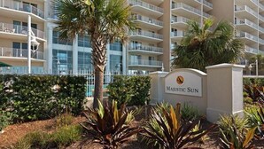 Et hotel med flere etager, altaner, palmer og et skilt med teksten 'Majestic Sun'.