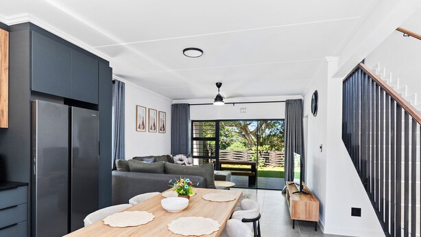 A modern kitchen with a dining area, a staircase, and a view of the outdoors.
