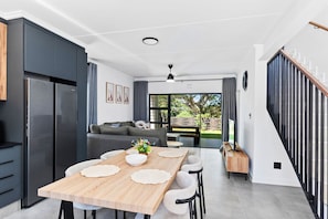 Una cocina moderna con comedor, una escalera y vistas al exterior.
