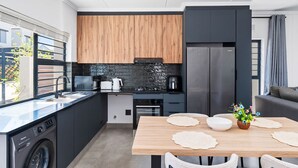 A modern kitchen with a dishwasher, oven, and a dining area with a table and chairs.