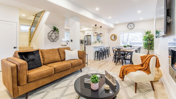 En moderne stue med en brun sofa, et sofabord og et spiseområde med stole og et bord.